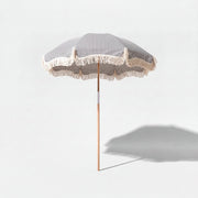 Betty's beach umbrella in dark navy and white stripe on a grey studio background with shadow