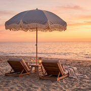 Betty's beach umbrella over two beach chairs at sunset with rose and a lantern