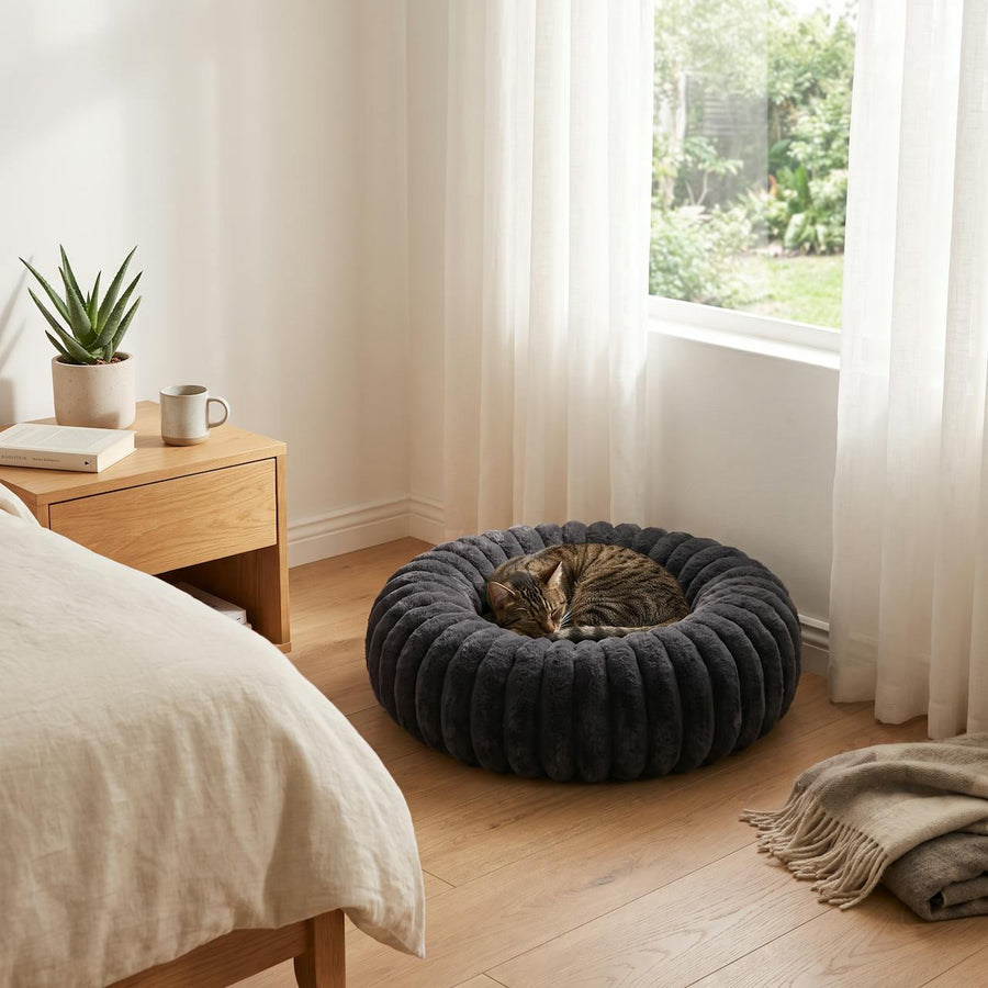 WuFF Donut Pet Bed in a bedroom corner with a cat curled up asleep in it