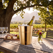 Gold ice bucket with white wine on a wooden table on a Cape Winelands wine farm