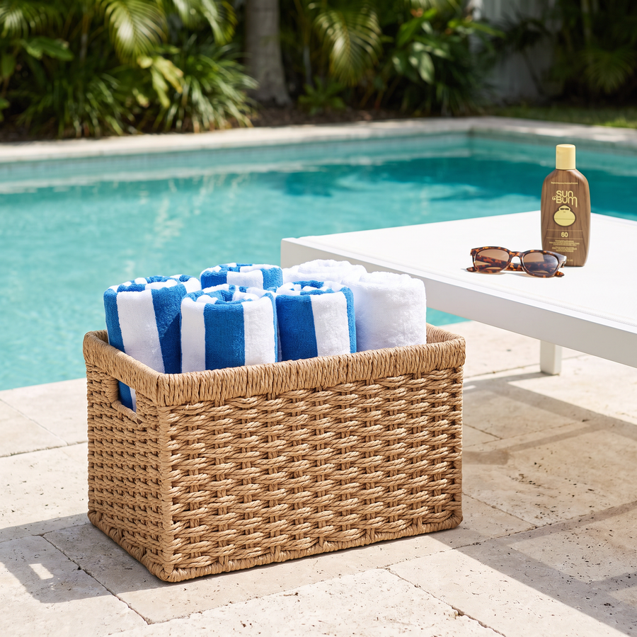 Woven wicker storage basket with rolled pool towels on a pool patio