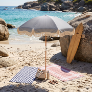 Betty's beach umbrella in a granite boulder cove with towels and a surfboard