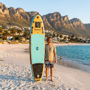 Standing with the Deadtree Wave Glide SUP on Camps Bay beach below the Twelve Apostles