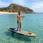 Paddling the Deadtree Odyssey SUP in clear water at Plettenberg Bay with Robberg behind
