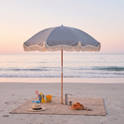 Betty's beach umbrella over a family picnic blanket on the beach in the morning