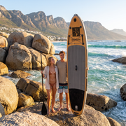 Couple with the Deadtree Odyssey SUP among the boulders at Llandudno beach