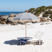 Navy Monaco beach umbrella on a white sand beach with a lounger and cooler bag
