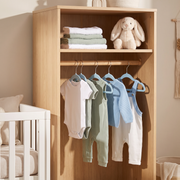 Blue velvet baby hangers with baby clothes in a modern nursery cupboard