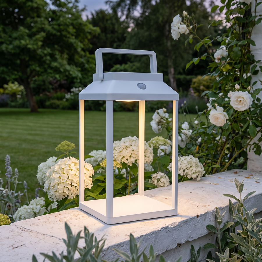 White LunaShine solar lantern on a garden wall among hydrangeas and roses