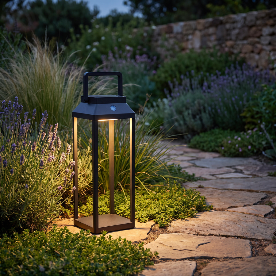 Black LunaShine solar lantern glowing beside a garden path at dusk