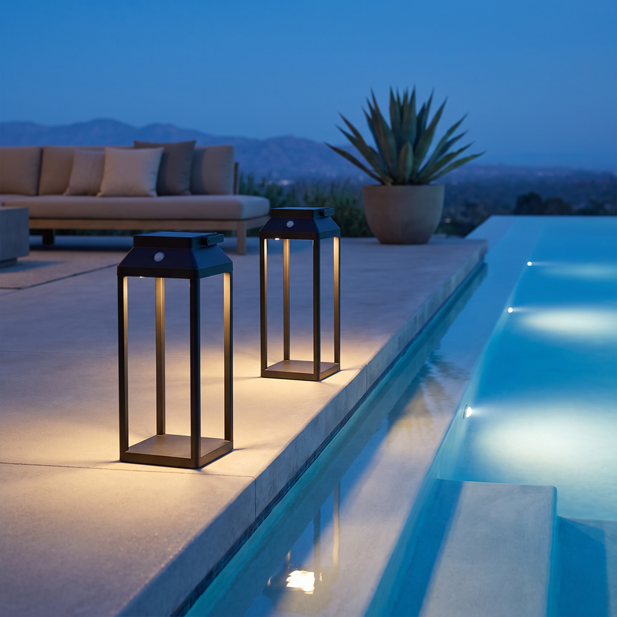 Two black LunaShine solar lanterns on an infinity pool deck at blue hour