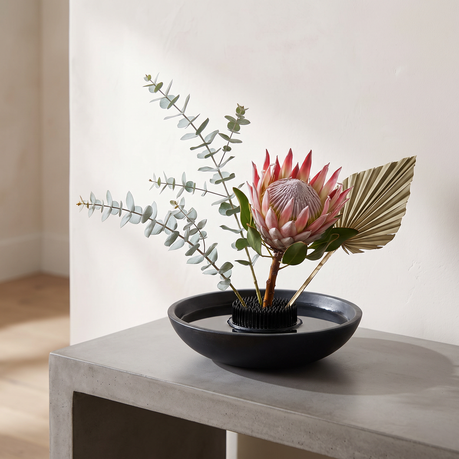 Needle Bloom flower holder in a black stone bowl with a king protea arrangement
