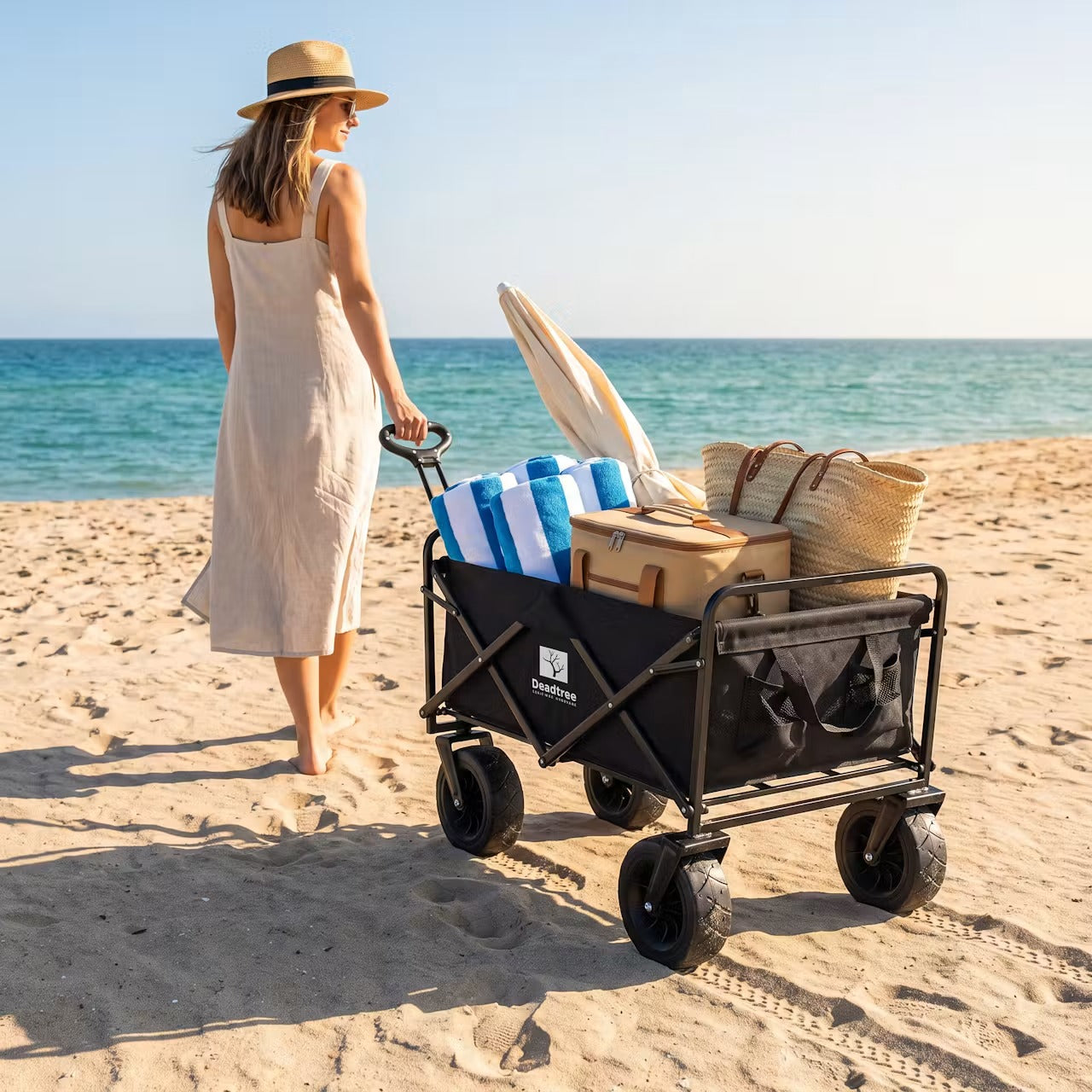 Woman pulling the Deadtree Rover trolley loaded with beach towels across the sand