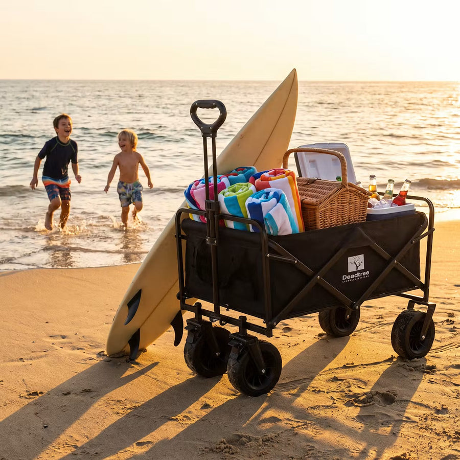 Deadtree Rover trolley packed with beach gear at sunset with a surfboard