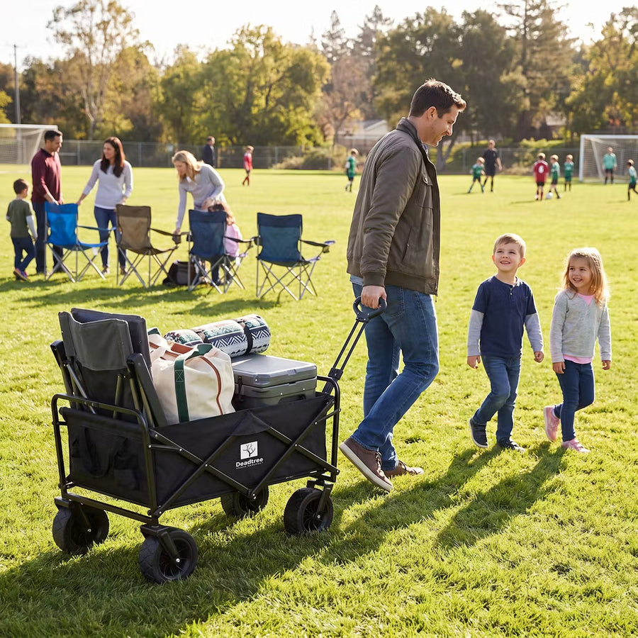 Dad pulling the Deadtree Rover trolley with chairs and a cooler across a sports field
