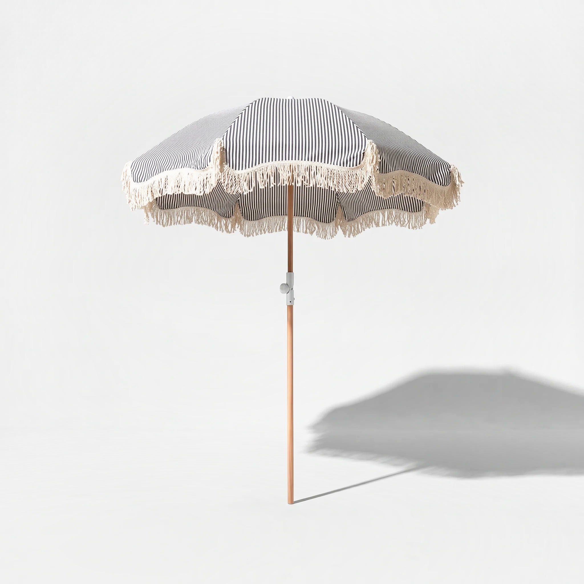 Monaco beach umbrella in dark navy and white stripe on a grey studio background