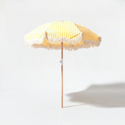 Monaco beach umbrella in yellow and white stripe on a grey studio background