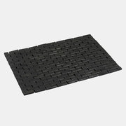 Black bamboo non slip bath mat, angled view on studio grey