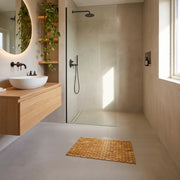 Brown bamboo non slip bath mat in front of a walk-in shower in a modern bathroom